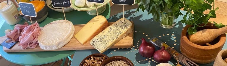 Gourmet cheese board with blue cheese, ham, nuts, and fresh herbs on a rustic table.