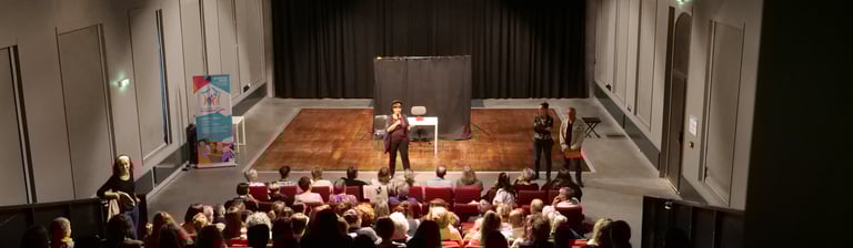 vue arrière large du public avec sur scène 1 femme forum accueil handicapés