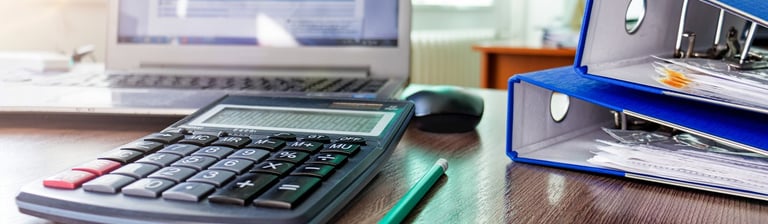 a desk with a calculator and a laptop