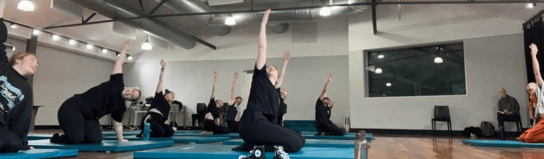 a group of people doing yoga exercises on a wooden floor