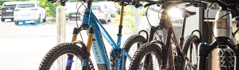 A row of modern full-suspension mountain bikes on display inside a professional bike shop.