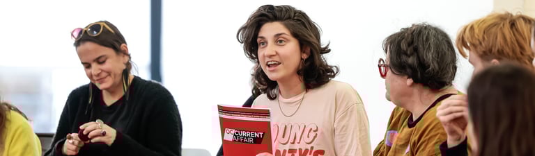 A person holding an education resource booklet up and smiling.