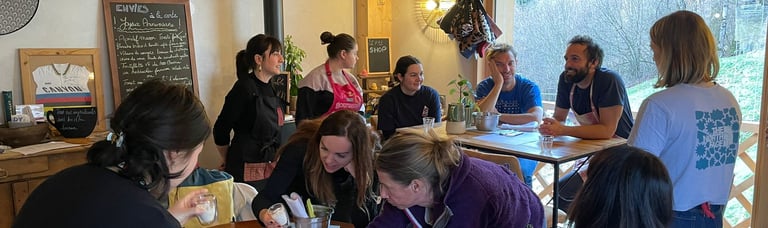 A group of people participate in a creative workshop at a wooden table in a rustic lodge.