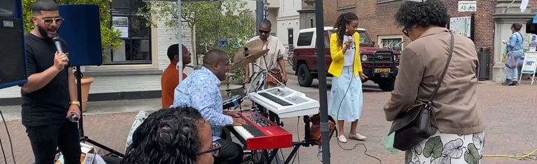 a group of people standing around a piano outside singing