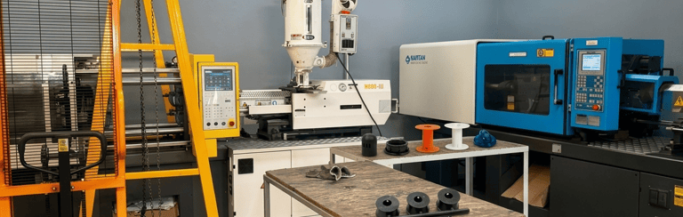 Industrial plastic injection molding machine with pallet jack and molded parts in a factory.