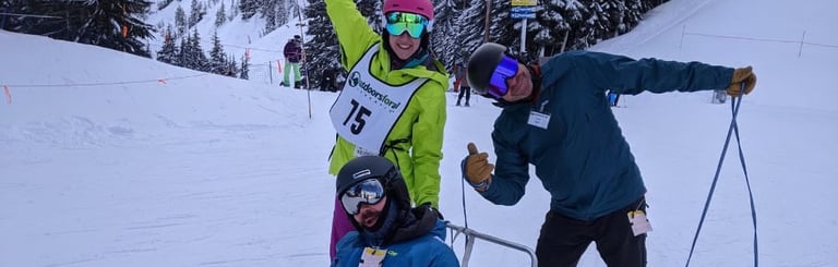 alt="Sean in his sit ski with Outdoors for All instructors Kristin and Ted, posing for the camera