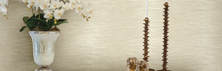Elegant cream textured wallpaper behind a modern console table with white orchids and gold candle holders.