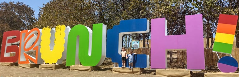 a young girl and boy standing in front of a large sign that says, 'brunch"
