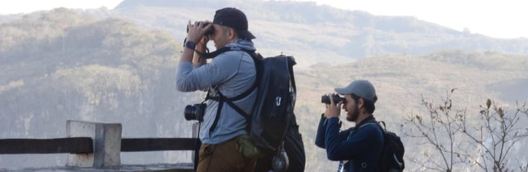 Two birdwatchers at Sumidero Canyon Chiapas look through their binoculars with a mountain backdrop