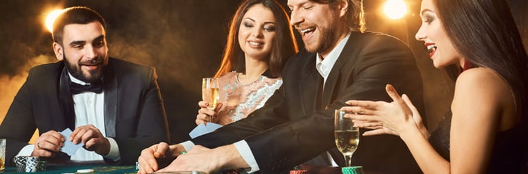 Cilvēki ballītē ar dzērieniem spēlē kāršu spēli uz kazino galdiņa