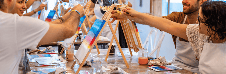 Cilvēki gleznošanas meistarklasē ar vīnu