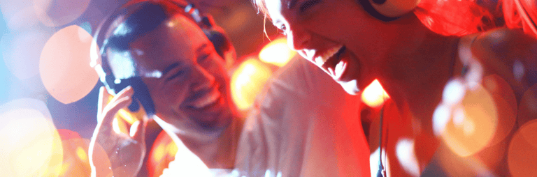 Smaidīgs vīrietis un sieviete ballītē ar austiņām