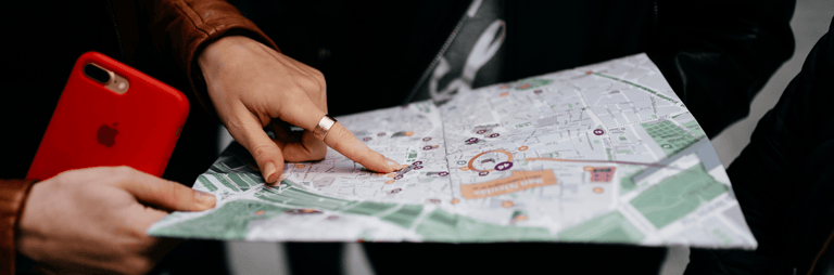 Cilvēki skatās fiziskā kartē un rāda uz vietu