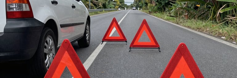 Tow truck assisting a stranded car on a roadside at dusk with city lights in the background.