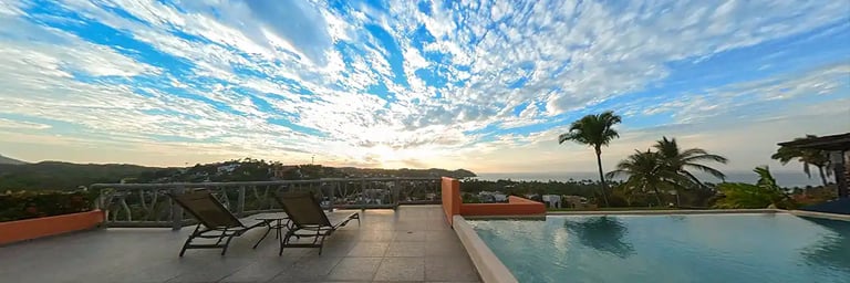 a pool with lounge chairs and a view of the ocean