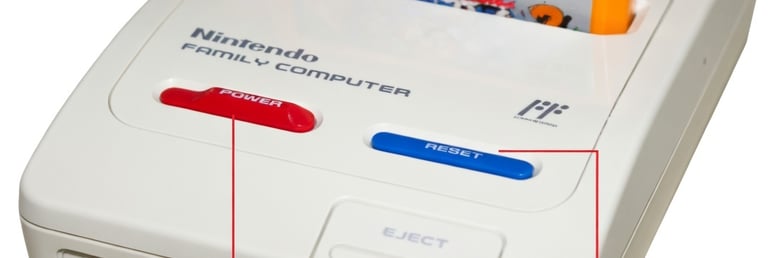 Adaptador Famicom mostrado de cima com cartucho encaixado no slot, todos os botões e conectores