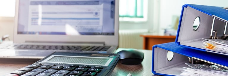 a desk with a calculator and a laptop