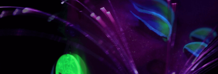An image of Illuma doing creative modeling, she is in the dark, holding a fiberoptic glowing whip