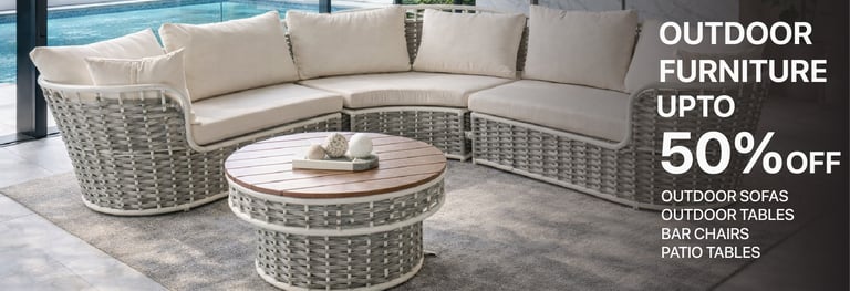 Modern woven wicker outdoor sectional sofa and round wood coffee table on a patio by a pool.