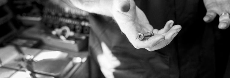 Photo de mains d'un artisan tenant une pièce détachée d'une lampe