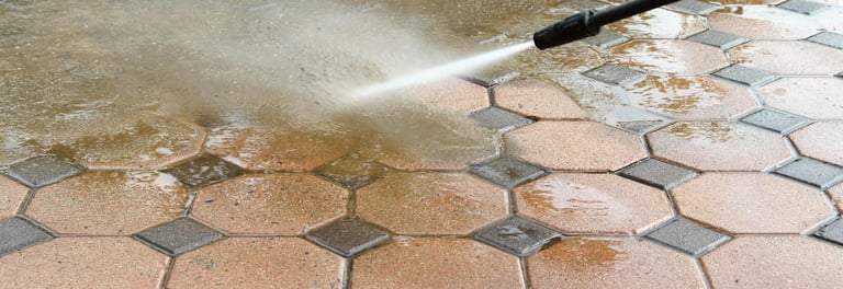 a person using a hose to clean a brick floor