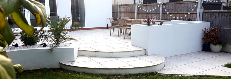 Modern chic raised porcelain patio with white rendered walls and planters
