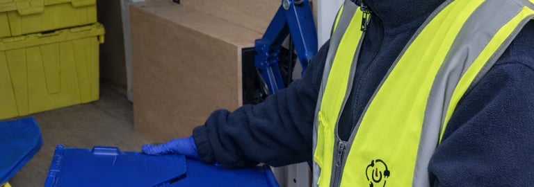 Female delivery driver in a high-visibility vest loading a security-sealed crate into our van.