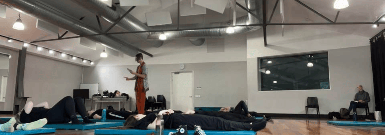 a man standing in a room with a woman on a yoga mat