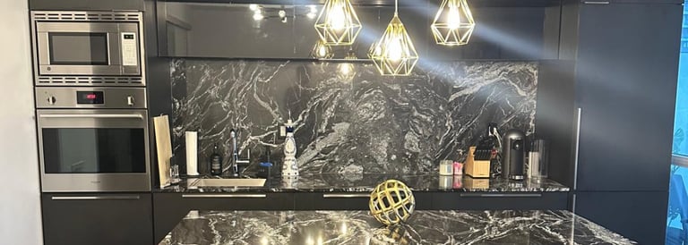 a kitchen with a marble counter top and black chairs