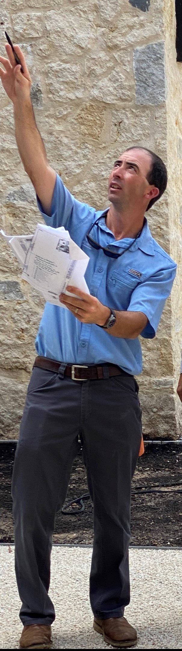 a man in a blue shirt is holding a cell phone designing lights on a house