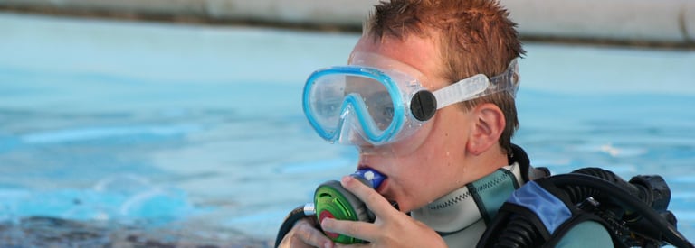 a boy in a diving suit and goggles in the water