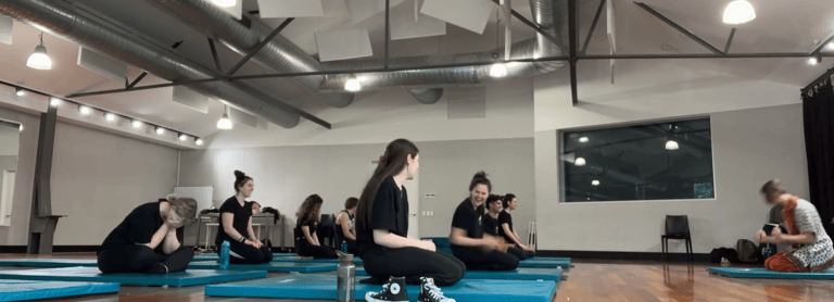 a group of people sitting on blue mats in a gym