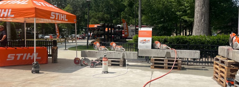 Stihl concrete saws and power equipment displayed at an outdoor demo event with orange tents.