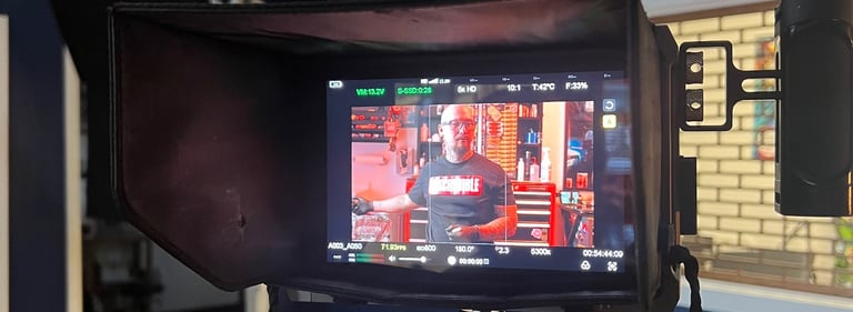 Professional film camera monitor displaying a man on set in a blue video production studio.