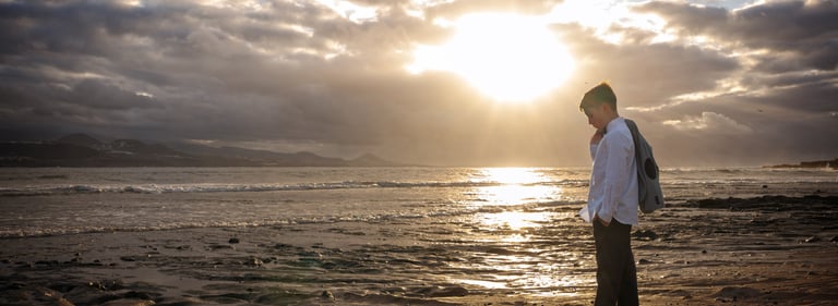 a man standing on a beach with a backpack