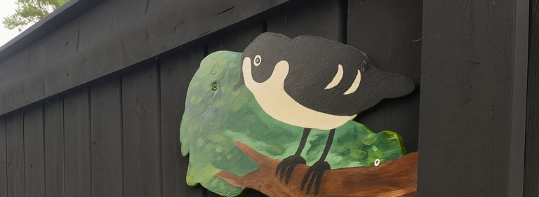 une cloture noire en peinture bois brule avec un oiseau peint pour decorer