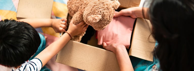 une femme maman et un enfant petit garçon emballe dans un carton un ours en peluche