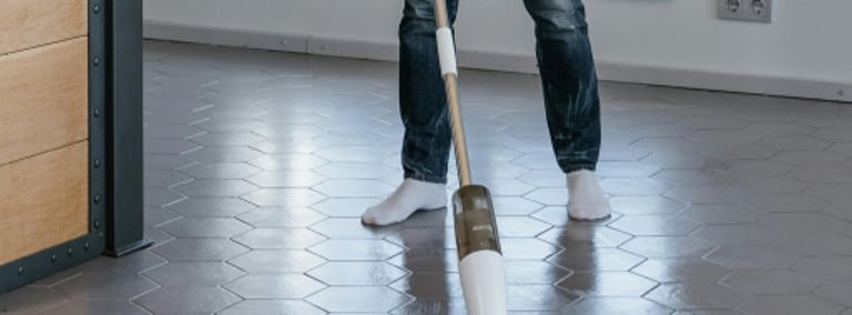 a woman in a kitchen with a mop cleaning the floor