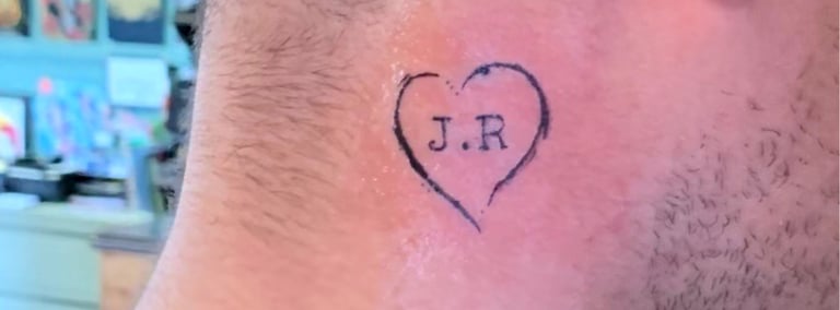 a man with a heart tattoo and the letters J.R. on his neck