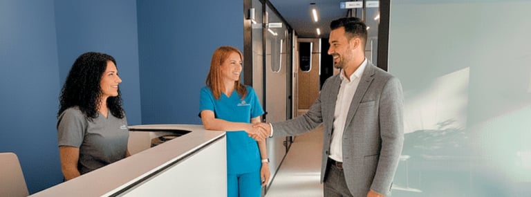 Un paciente estrechando la mano de una odontóloga en la recepción de una clínica moderna,