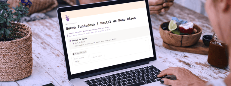 Woman working on a laptop displaying the Nodo Rizom website portal while sitting at an outdoor table.