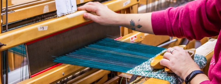 Student using a floor loom in one of our weaving classes.