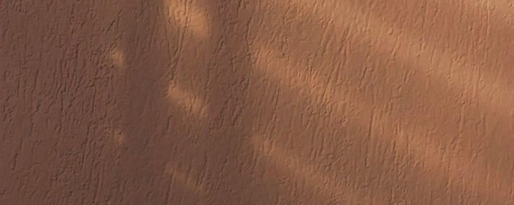 An orange walls with shadows of blinds being cast on the for LVF.LVX's shadow work website.
