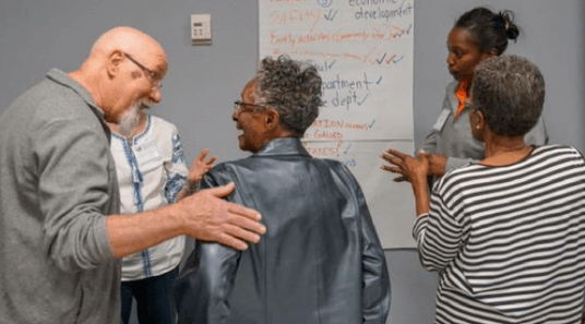 a group of people standing around a white board