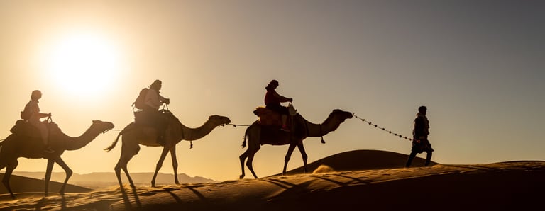 a group of people riding camels in the desert