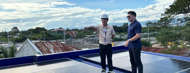 An engineer and client inspecting a residential rooftop solar panel installation under a blue sky.