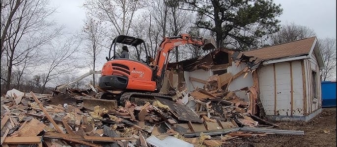 a excavator is parked in front of a demoed house