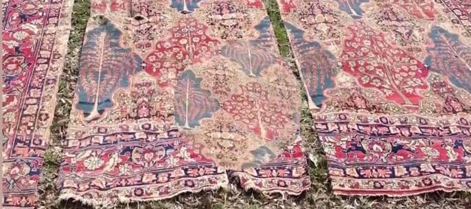 Antique rug with severe tearing and damaged sections before professional restoration