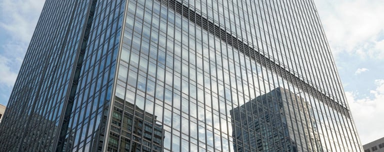A stunning architectural shot of a glass and steel skyscraper in a major North American city, reflecting the sky and representing stability and innovation.