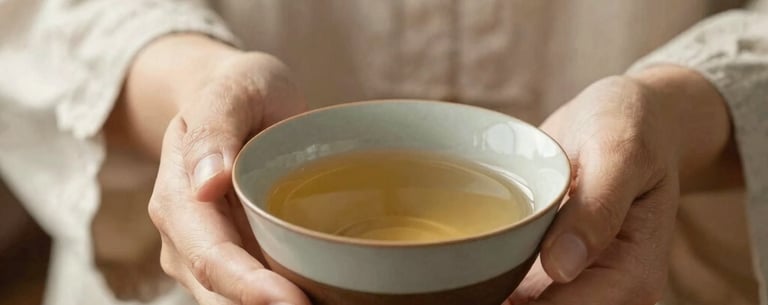 A woman's hands gently holding a ceramic bowl of tea, soft sunlight, focus on the texture of the linen clothes and the earthy tones of the pottery, calm and nurturing mood.